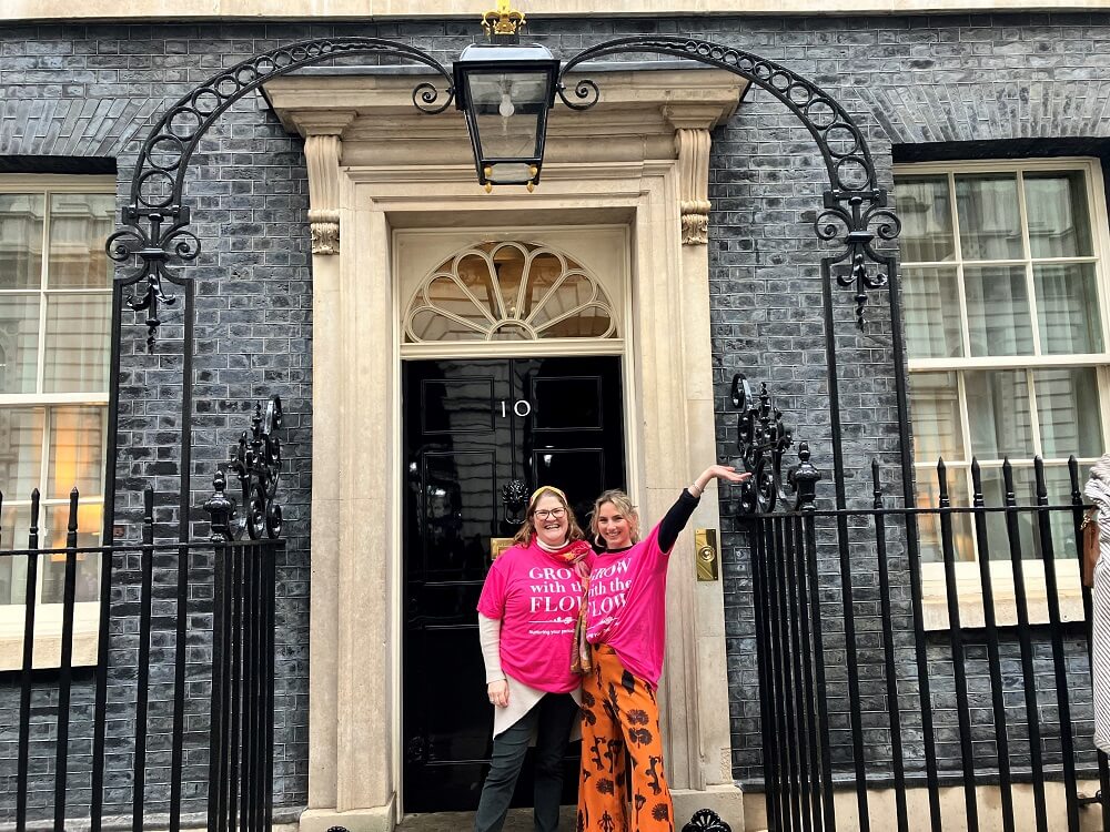 Suzanne Hunnable-Letch and Carolina Skoog standing outside Number 10 Downing Street wearing Grow with the Flow t-shirts to promote the All In project to help improve menstrual health support in Halstead, Essex.